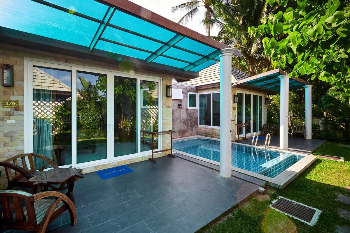 Une maison moderne dotée d’une piscine, de grandes portes vitrées et d’un patio couvert.