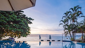 A poolside view with a table, umbrella, and tropical plants. - Sea Valley Resort (Koh Samui)