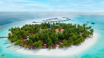 An aerial view of a tropical island resort with overwater bungalows, a white sandy beach, and clear turquoise waters.