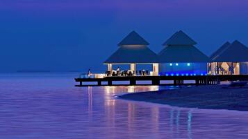 A waterfront resort with overwater bungalows connected by a dock.