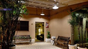 An indoor courtyard with a tiled floor, two benches, potted plants, and a door leading to another room.