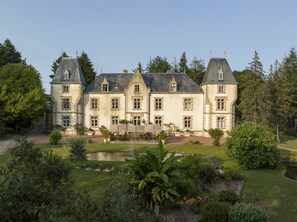 A large, historic building with multiple windows and a symmetrical facade, surrounded by lush greenery and a small pond. - Domaine du Boisniard (Chanverrie)