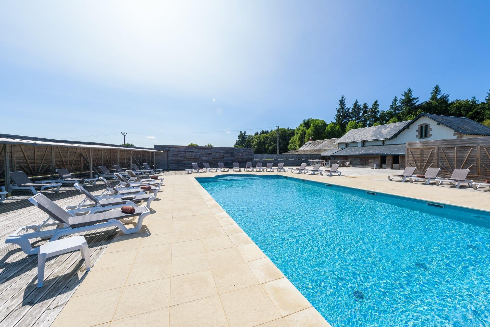 Un espace piscine avec des chaises longues et un bâtiment en arrière-plan.