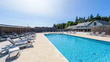 Un espace piscine avec des chaises longues et un bâtiment en arrière-plan.