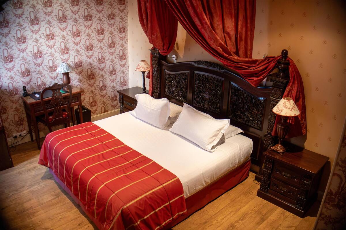 A neatly made bed with a red and white striped bedspread, two bedside tables with lamps, and a wooden headboard.