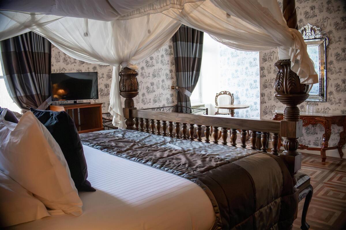 A bedroom with a large bed, a television, and a mirror.