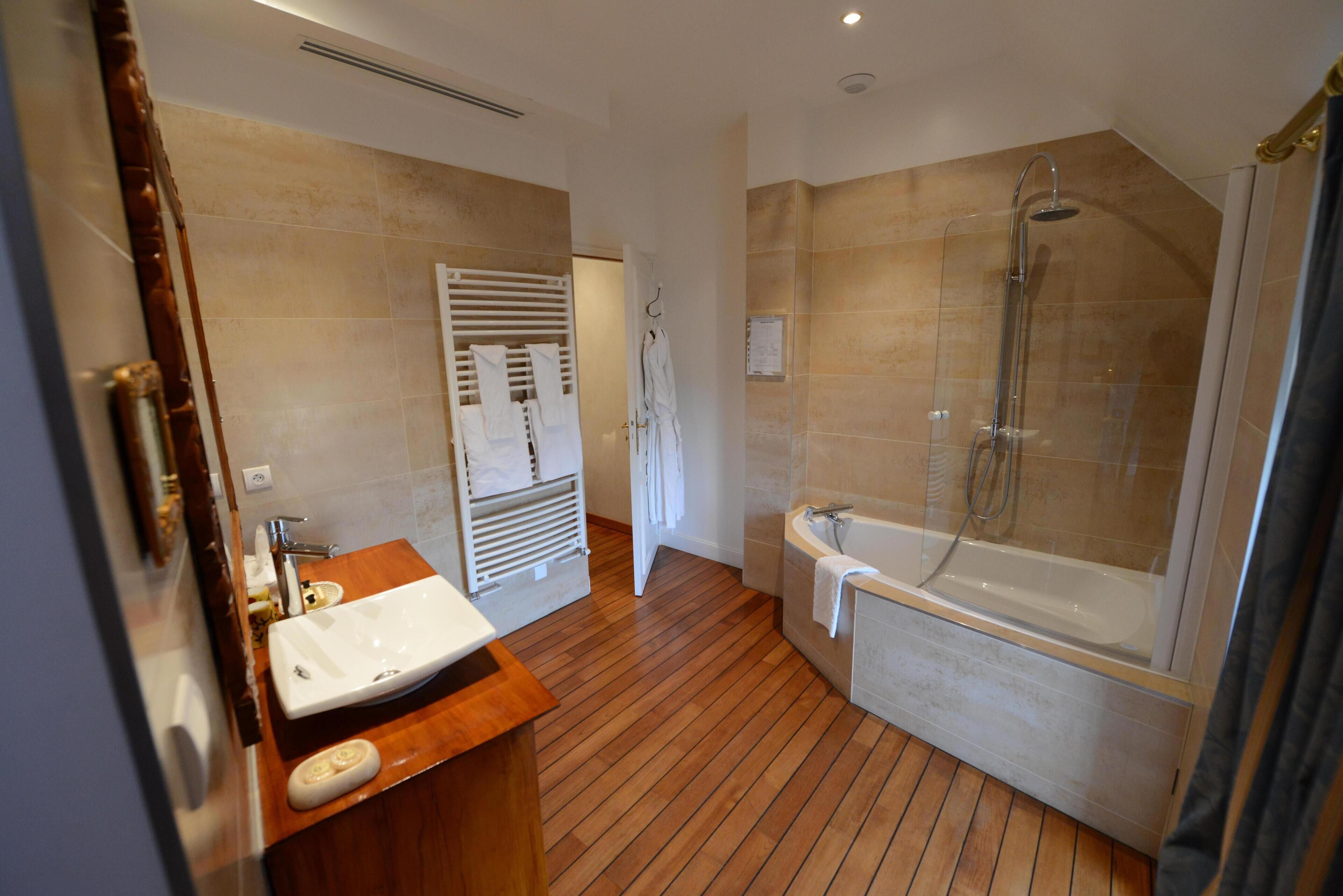 Een moderne badkamer met een houten wastafelmeubel, een badkuip en een douche met glazen wanden.