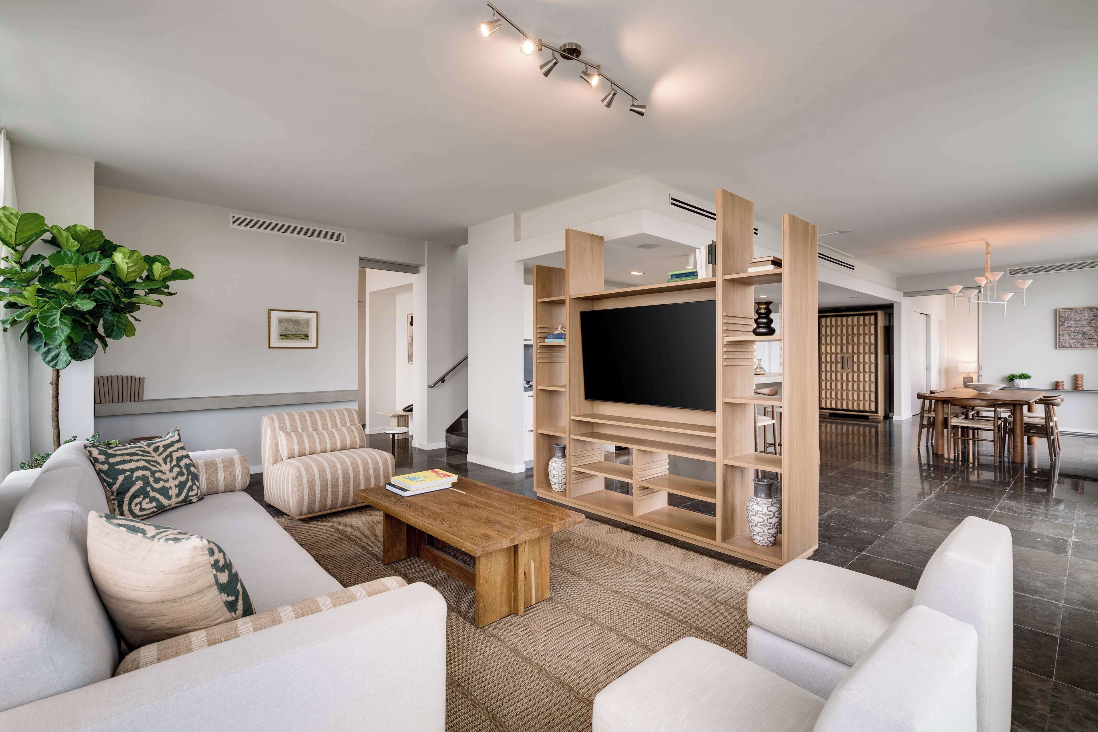 Una sala moderna con un sofá, una mesa de centro y un mueble de TV con estanterías.