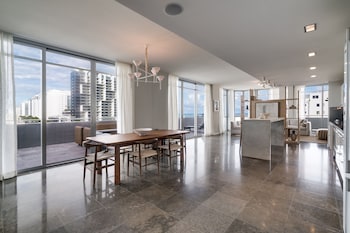 A modern kitchen with a central island, white cabinetry, and a dining area with a white sofa and chairs. at Boulan South Beach