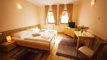A hotel room with a wooden bed, bedside tables, a desk with a chair, and a television.