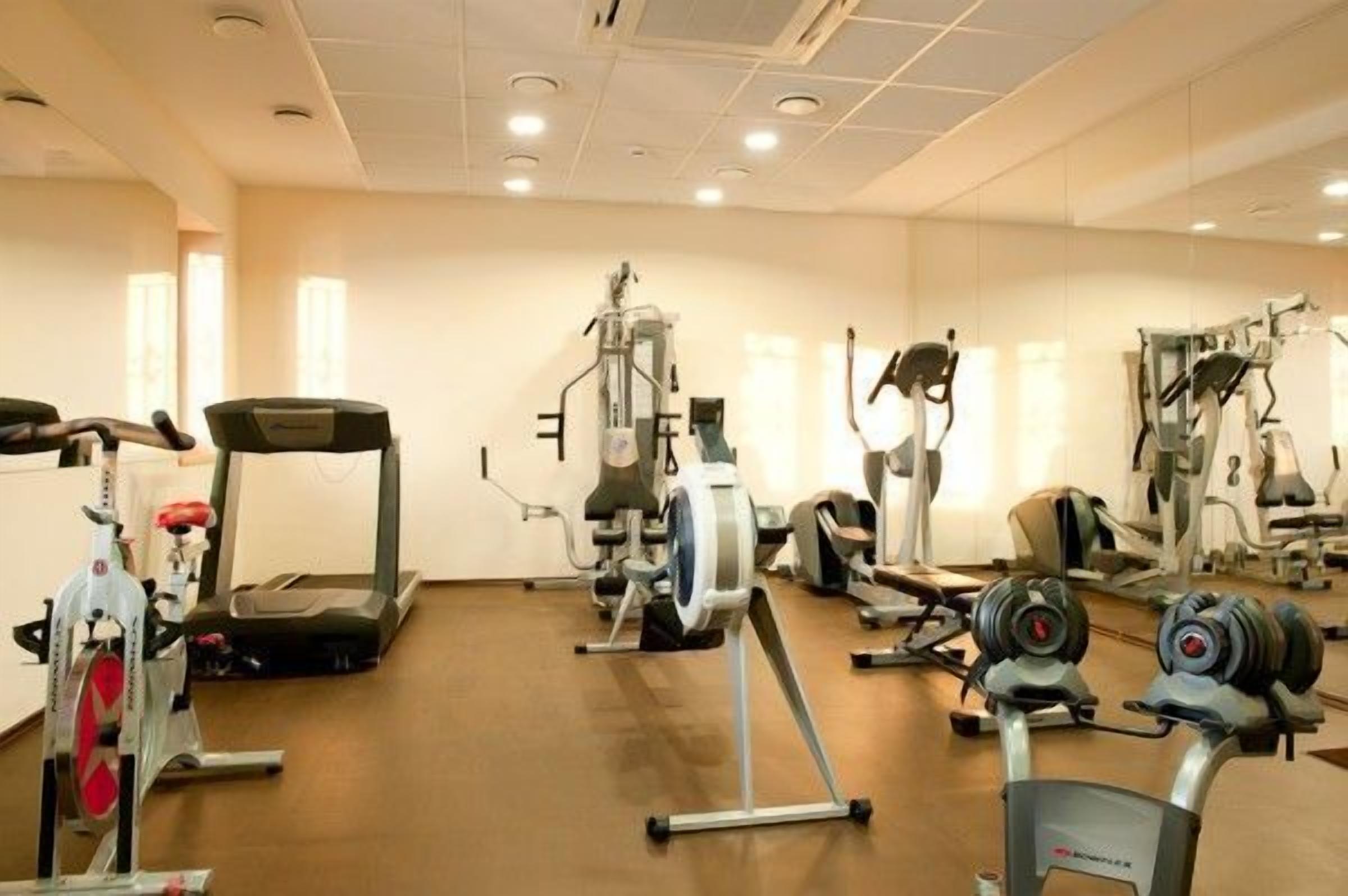 Un gimnasio con cintas de correr, máquinas de pesas y pesas libres.
