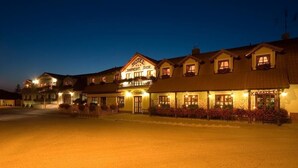 A hotel with a prominent sign, multiple windows, and a well-lit entrance. - Hotel Karpatsky Dvor (Lozorno)