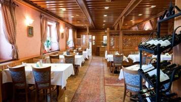 A restaurant with wooden interiors, white tablecloths, and a central aisle.