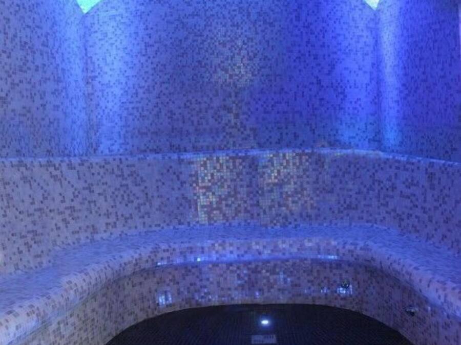 A stone-walled sauna with a curved bench and a tiled floor.