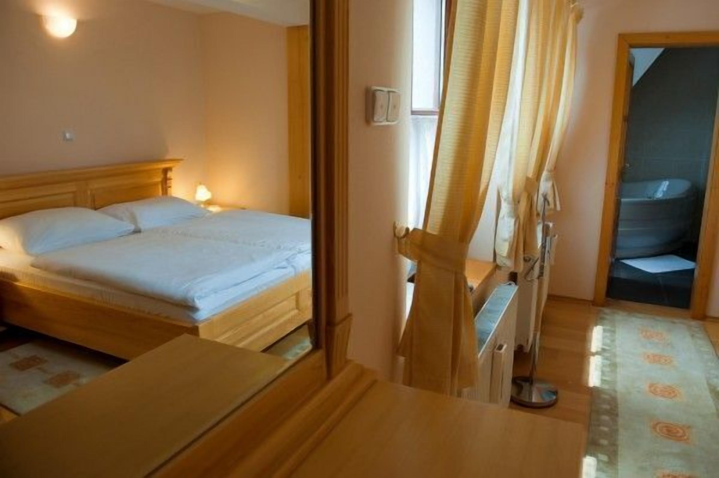 A bedroom with a wooden bed, a bedside table, and a window with curtains.