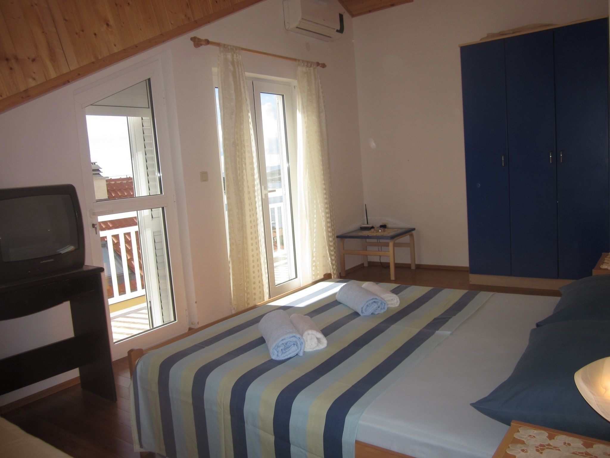 Un dormitorio con cama, televisión, escritorio y armario.