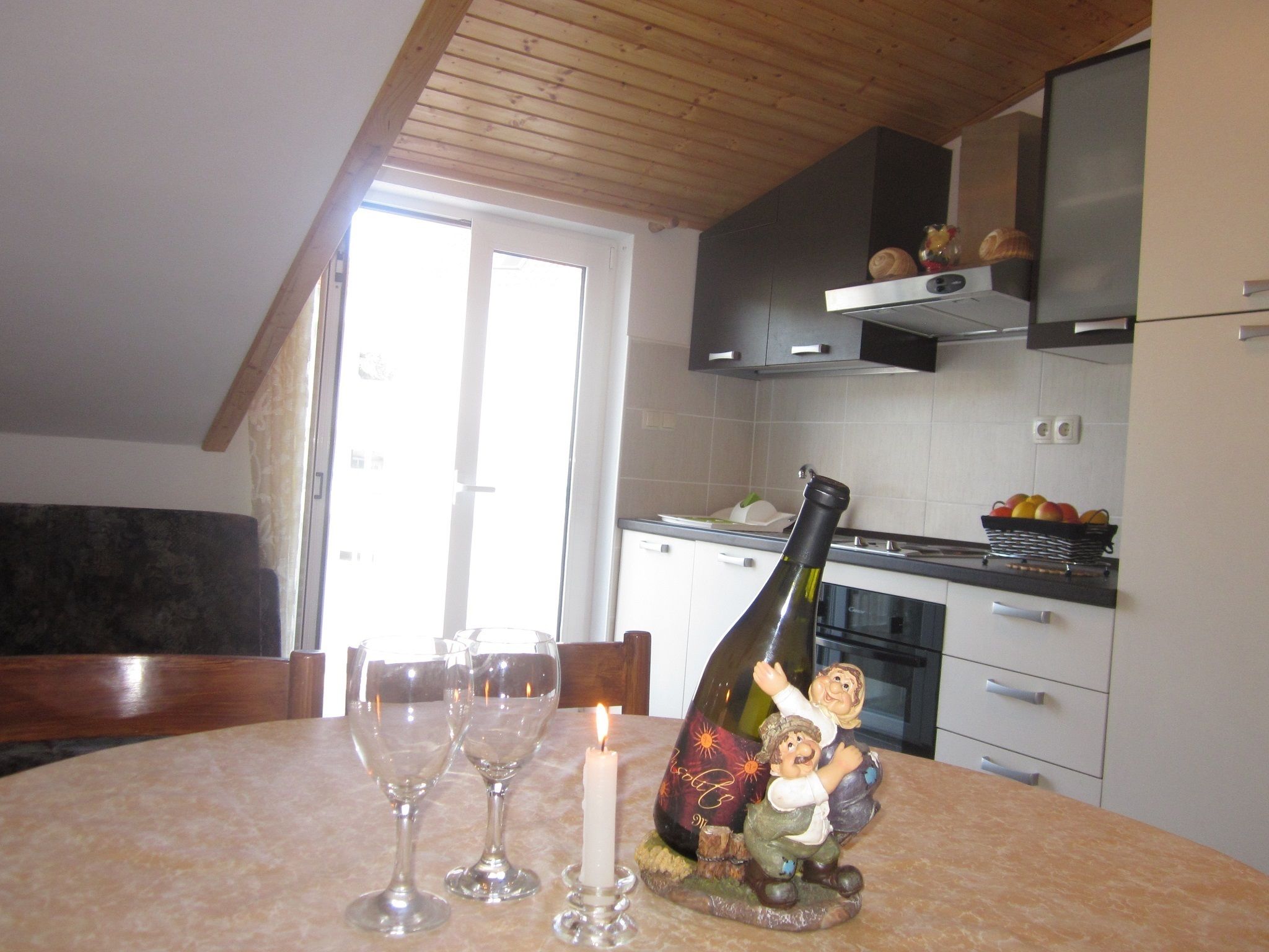 A dining area with a table set for two, a bottle of wine, and a candle.