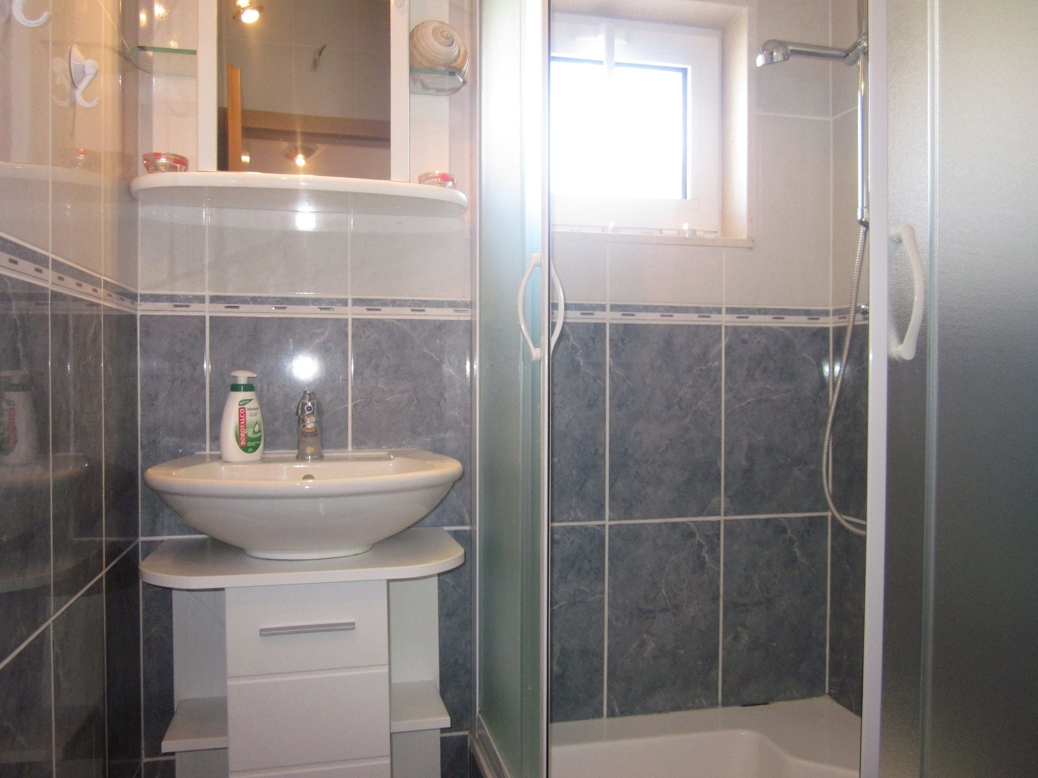 A bathroom with a white sink, a mirror, and a shower.