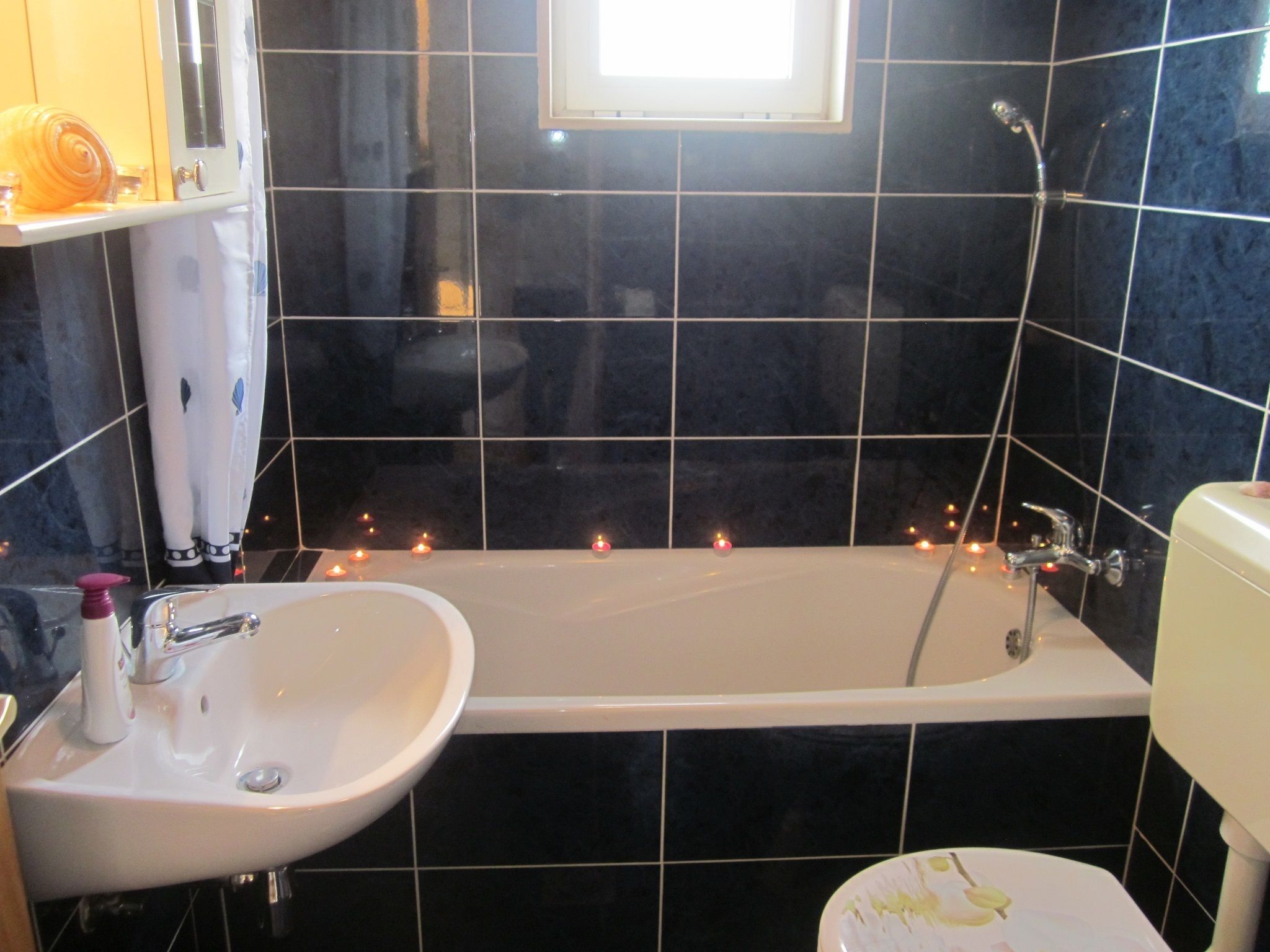 A bathroom with a bathtub, sink, and toilet. There are candles on the floor.
