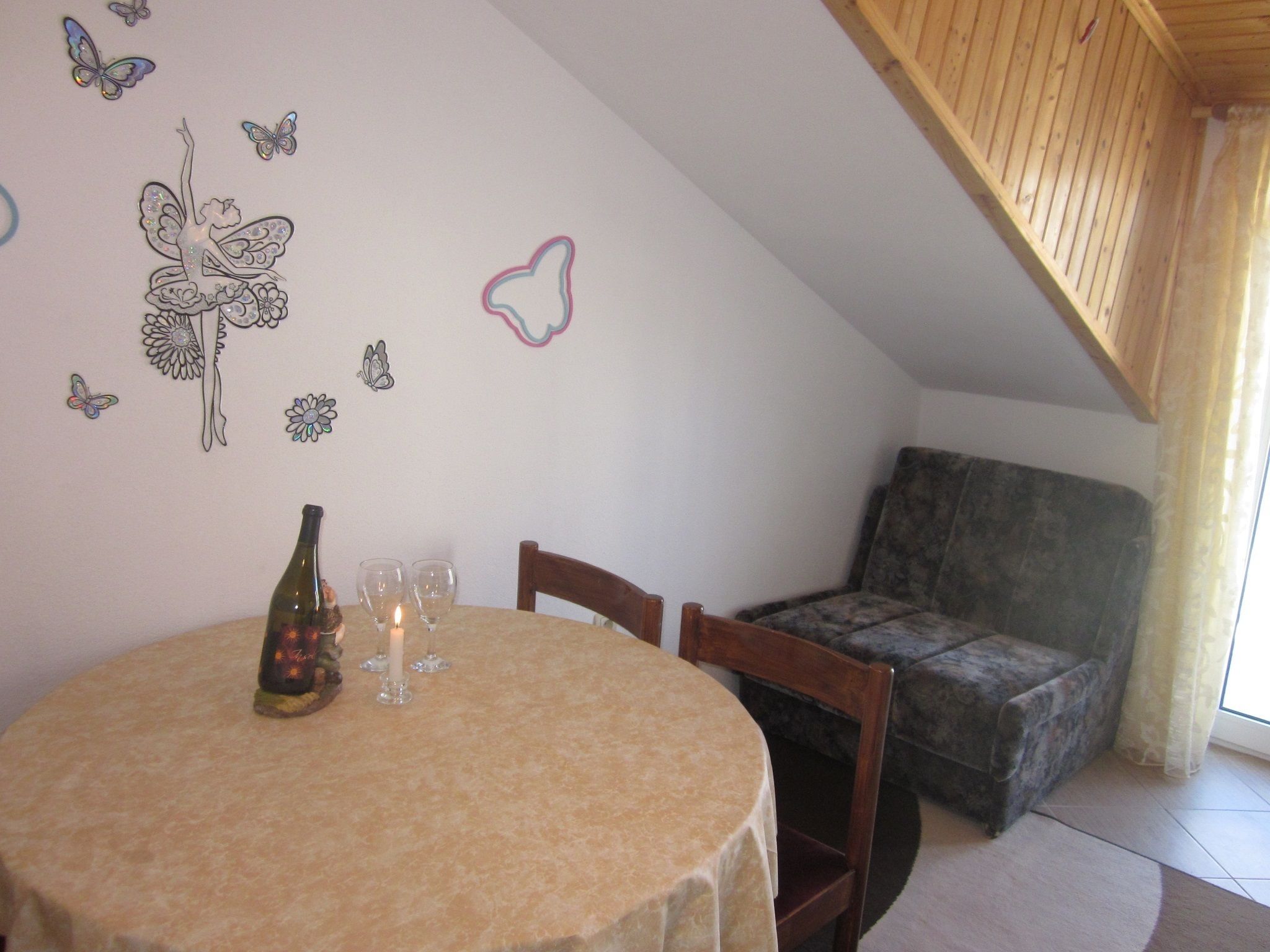 A cozy room with a round table, two chairs, a sofa, and decorative wall stickers.
