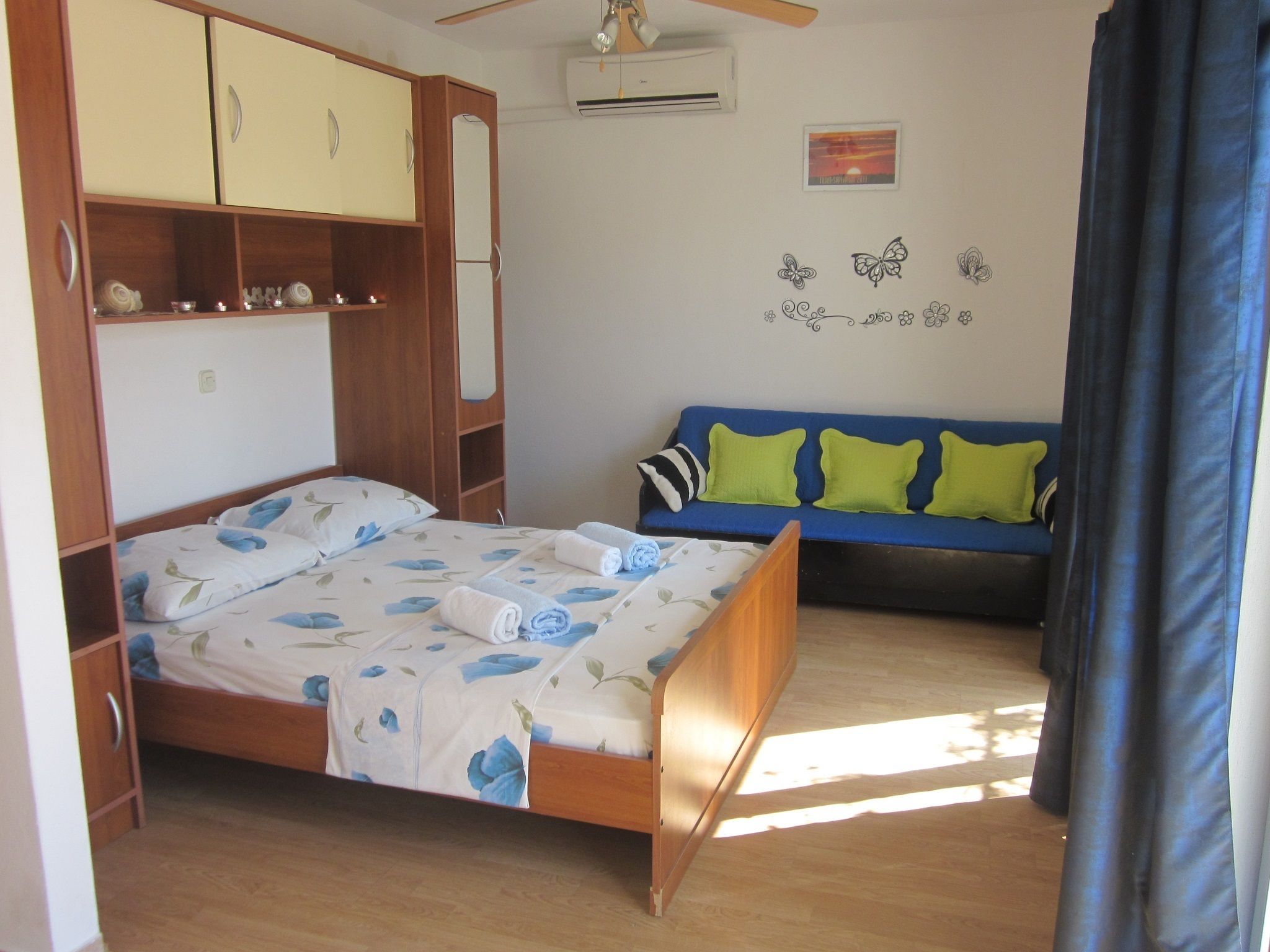 A bedroom with a bed, a wardrobe, a sofa, and a wall decoration.