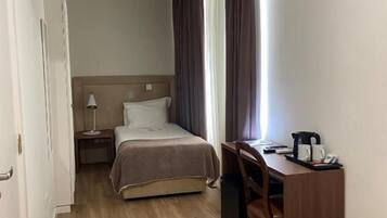 Habitación de hotel con cama, escritorio, silla, televisor y aire acondicionado.