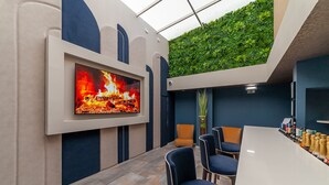 A modern lounge with a flat-screen TV, seating, a bar, and a green wall. - Hotel Porto Mar (Matosinhos)