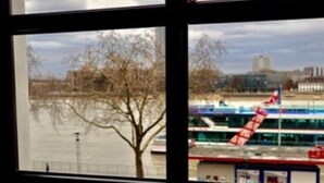 A view through a window of a river with a bridge and buildings in the background. - Löwenbräu Köln Hotel & Restaurant (Cologne)