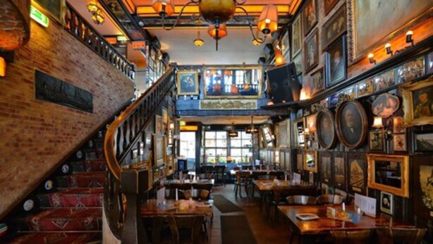 A restaurant with a brick wall, wooden staircase, and multiple tables and chairs. - Löwenbräu Köln Hotel & Restaurant (Cologne)