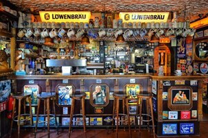 Un bar con varios taburetes, una barra con distintos productos y un letrero que dice "LOWENBRÄU".