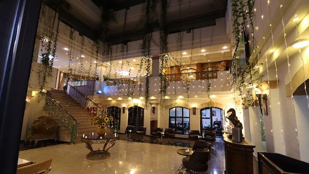 A spacious lobby with a high ceiling, hanging plants, and a staircase leading to an upper level.