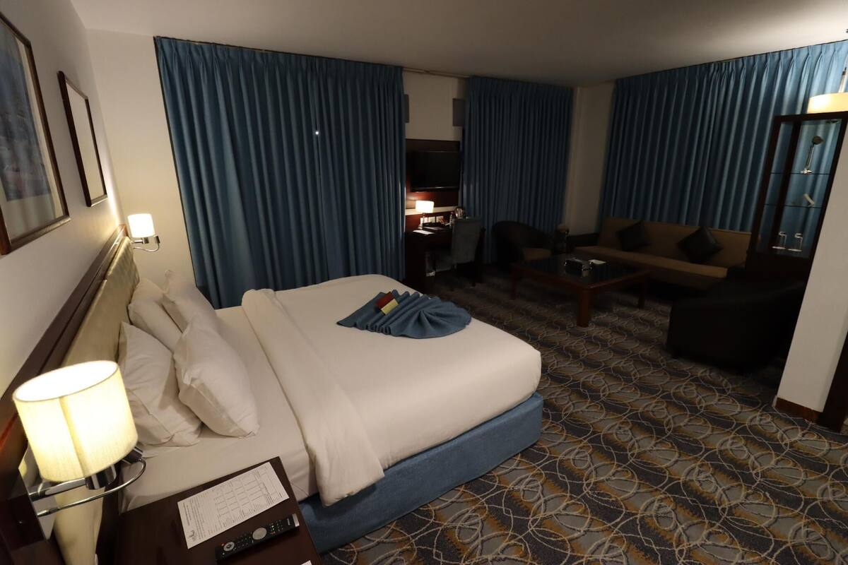 A hotel room with a bed, a desk, a chair, and a sofa.