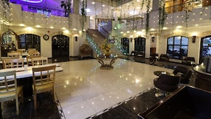 A spacious lobby with a central staircase, multiple seating areas, and hanging plants.