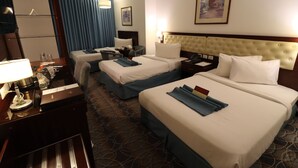 A hotel room with two beds, a desk with a lamp, a nightstand, and a large mirror.