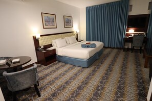 A hotel room with a large bed, a desk with a chair, a small table, and a TV. - Larsa Hotel (Amman)