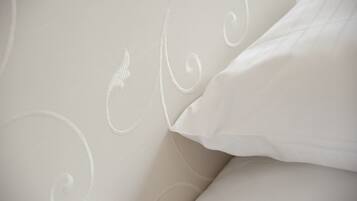 A close-up of a bed with a white headboard and pillows.