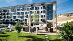 A modern hotel with a courtyard featuring outdoor seating and a large umbrella. - Cityhotel Design & Classic (St. Pölten)