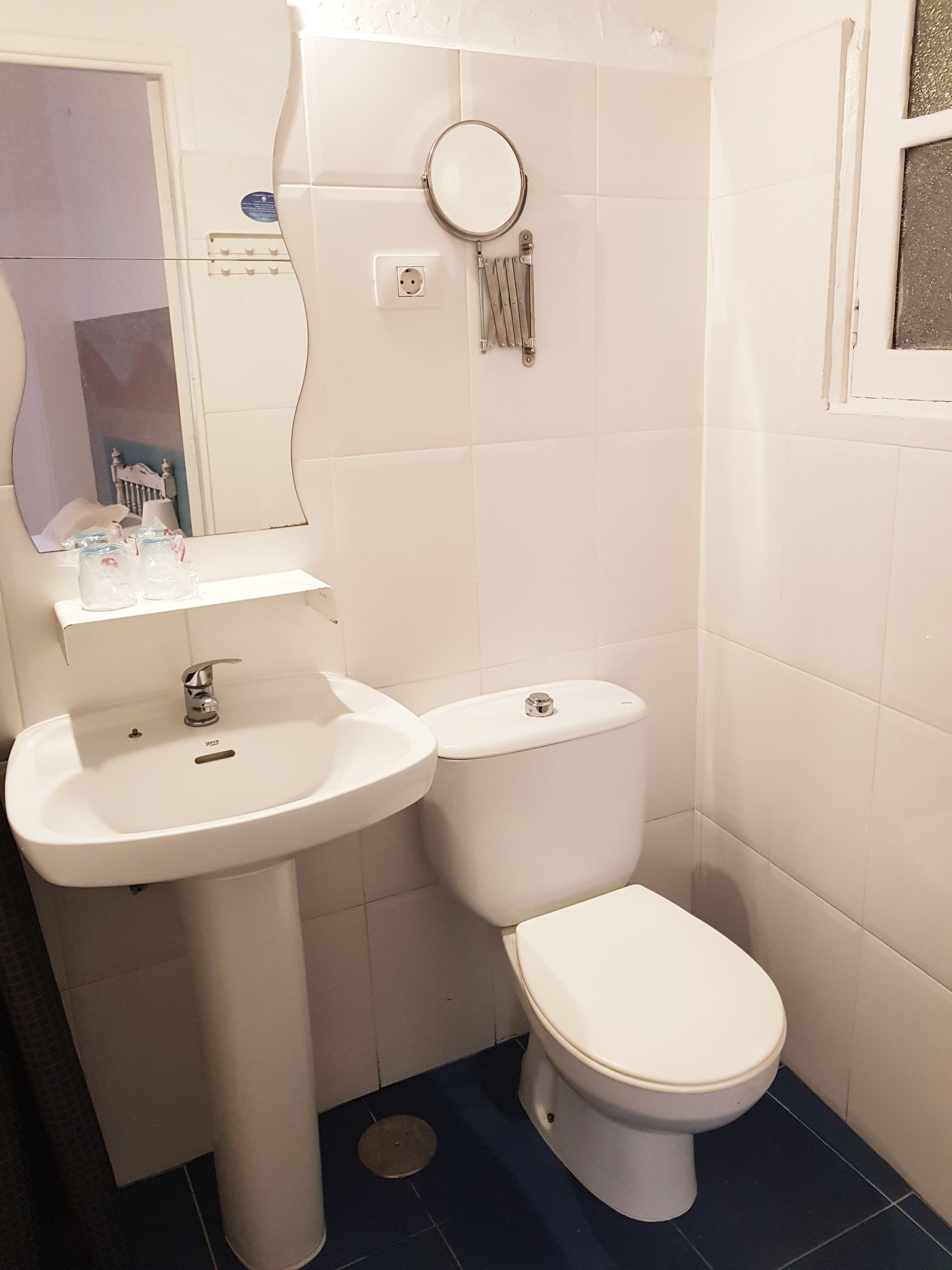 Een badkamer met een wit wastafel, toilet en spiegel.