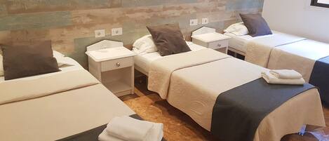 A hotel room with two beds, a nightstand, a small table, and a wall with a textured design.