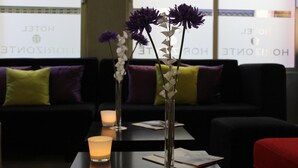 Een hotel lobby met een zwarte bank, een tafel met een kaars en vazen met bloemen.