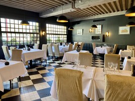 Un restaurante con suelo a cuadros, manteles blancos y sillas color beige.