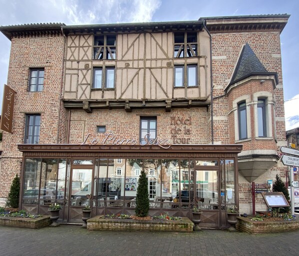Un hotel con fachada tradicional, ventanas amplias y un cartel que dice "Le Pierre Sudzé Tour".
