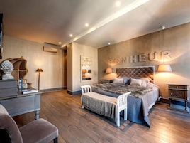 Un dormitorio con una cama grande, mesitas de noche, una silla y un letrero en la pared que dice "BONHEUR".