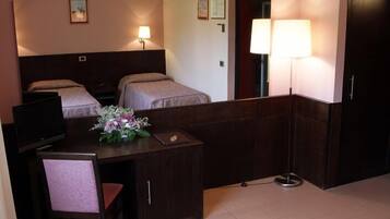 Una habitación de hotel con una cama, un escritorio con silla, un televisor, una lámpara y un espejo.