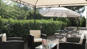 Un área de patio al aire libre con muebles de mimbre, un paraguas grande y una mesa de vidrio.