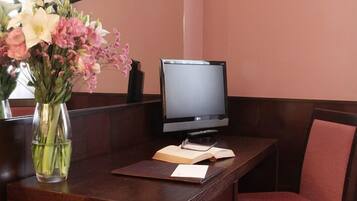 A reception desk with a computer monitor, a vase of flowers, and an open book.