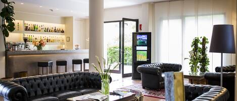 Una sala de estar moderna con un sofá de cuero negro, una mesa de centro y una zona de bar con estantes llenos de botellas.