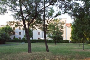 Um hotel com fachada branca, uma placa de identificação e uma área gramada com árvores.