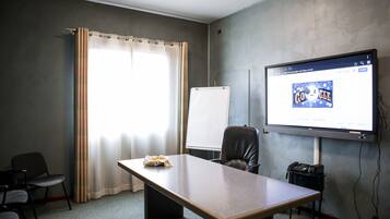 Une salle de conférence équipée d’une grande table, d’un tableau blanc, d’un écran de projection affichant le logo Google et d’un téléphone posé sur un bureau.