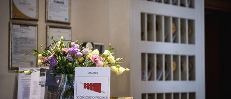 Mostrador de recepción con un florero, una tarjeta de membresía y un letrero de hotel.